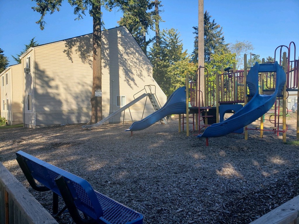 a playground with slides and benches in front of a building