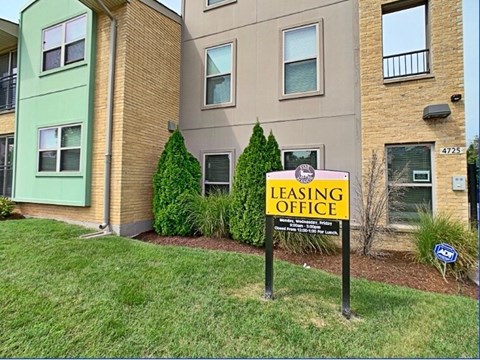 A leasing office sign is posted in front of a building.