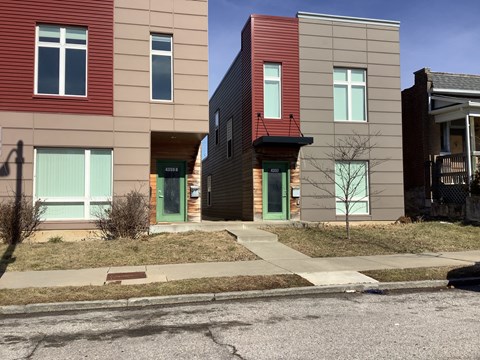 A row of modern townhouses with green doors and windows.
