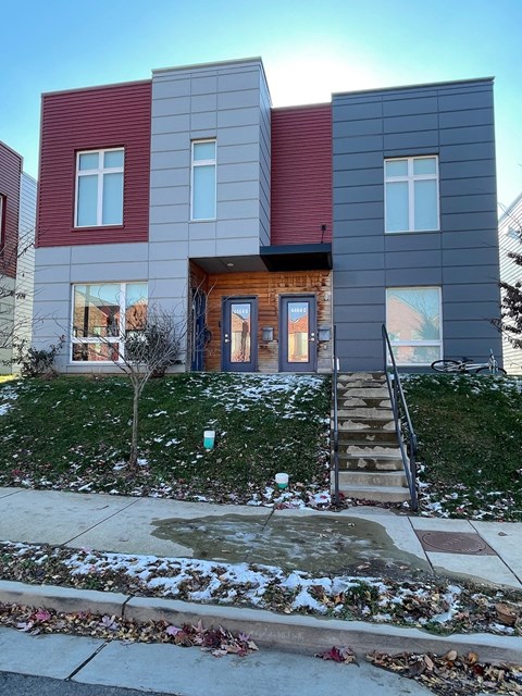 A modern house with a red and grey exterior and a wooden front door.
