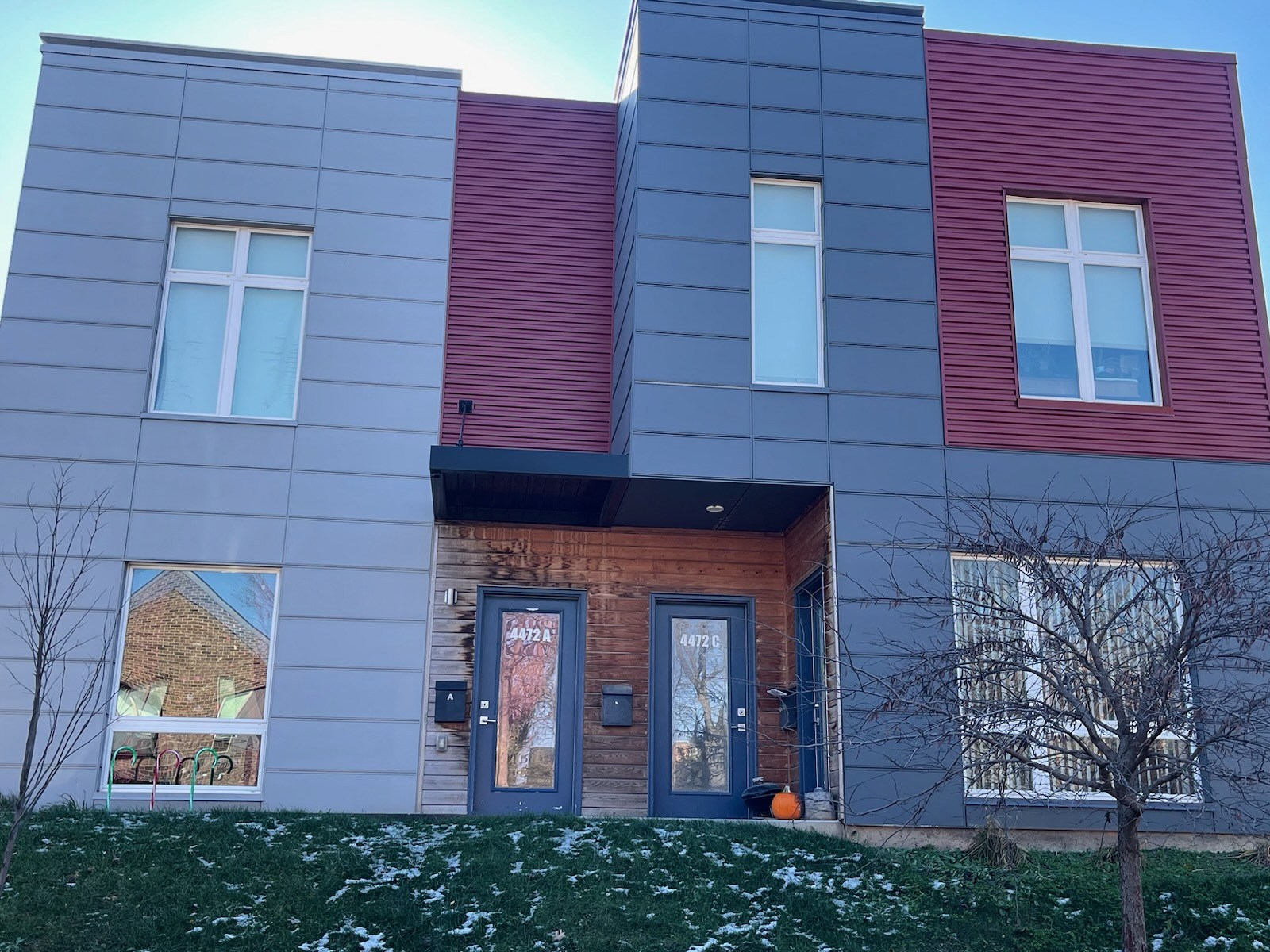 A modern house with a grey, red and blue exterior.