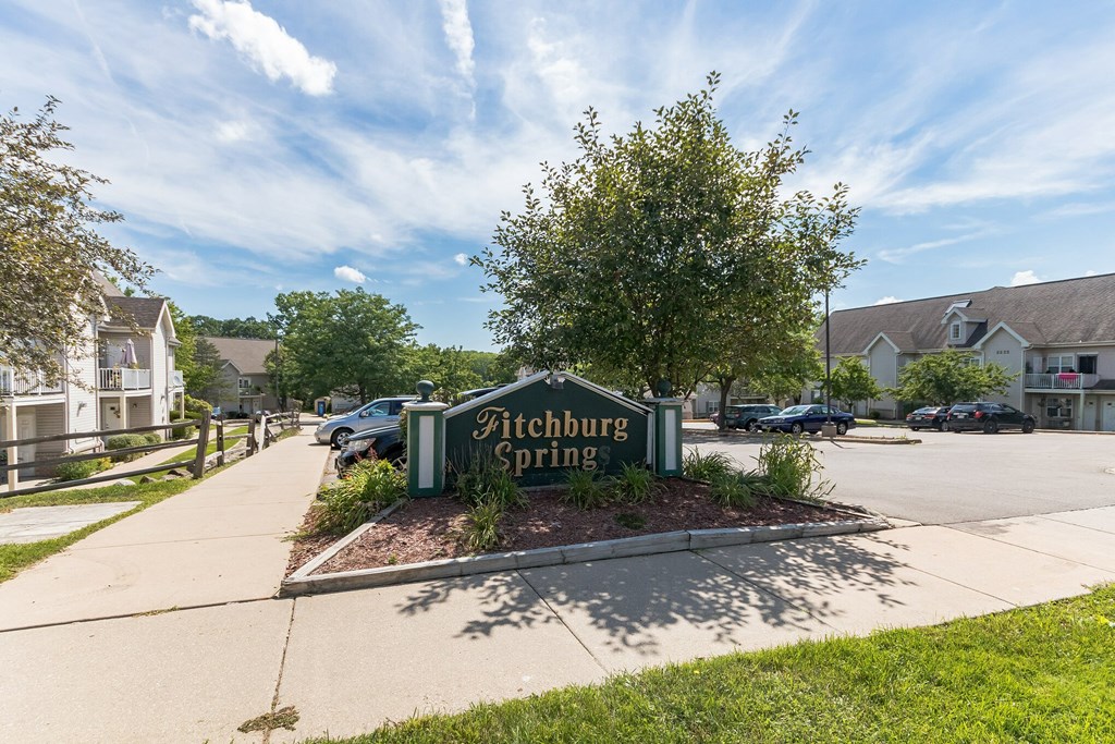 A sign that says Fitchburg Spring in front of some houses.