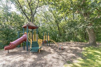 A playground with a red slide and green seating area.