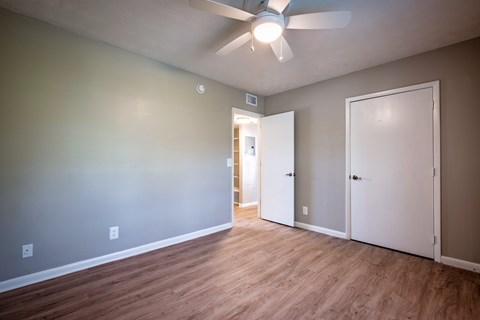 A room with a ceiling fan and two doors.