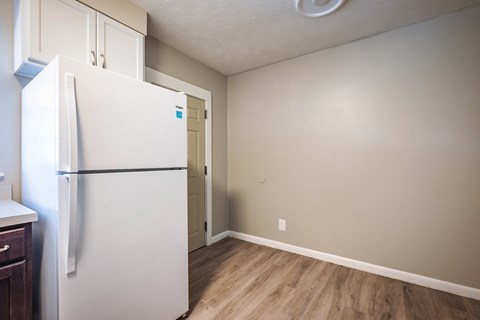 A white refrigerator in a kitchen with wood flooring.