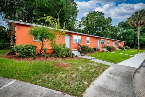 A row of orange houses with green trees in the background.
