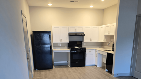 A kitchen with black appliances and white cabinets.