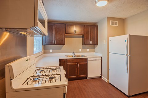 A kitchen with a white fridge, stove and dishwasher.