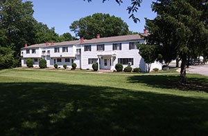 A white house with a green lawn in front.