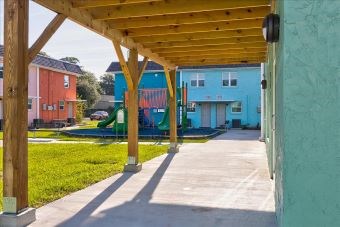 A playground area with a wooden pergola and a slide in the background.
