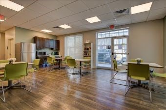 A room with a kitchenette and a dining table with chairs.