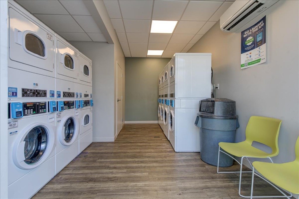 A laundromat with washers and dryers and a yellow chair.