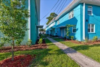 A tree is planted in a flower bed in front of a blue building.