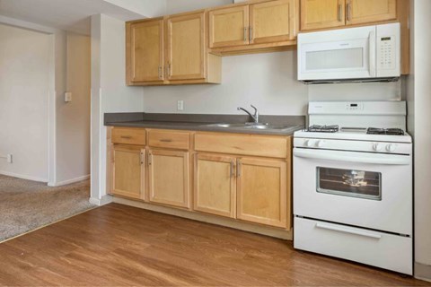 A kitchen with wooden cabinets and a white stove.