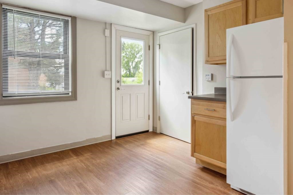 A kitchen with a white fridge and wooden floors.