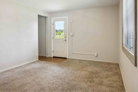 A room with a carpeted floor and a door leading outside.