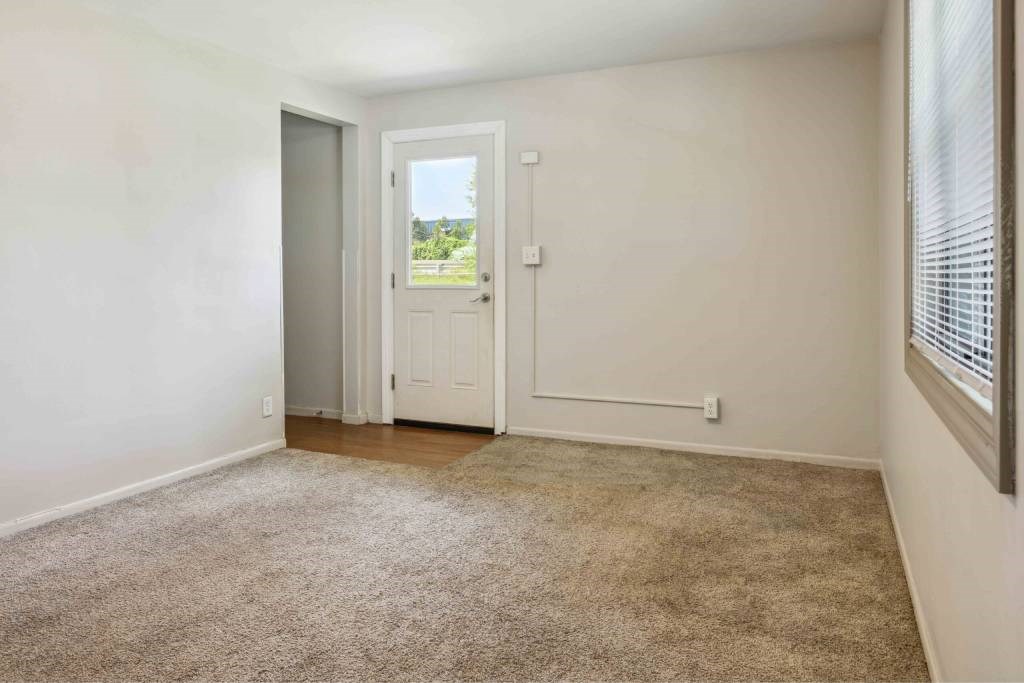 A room with a carpeted floor and a door leading outside.