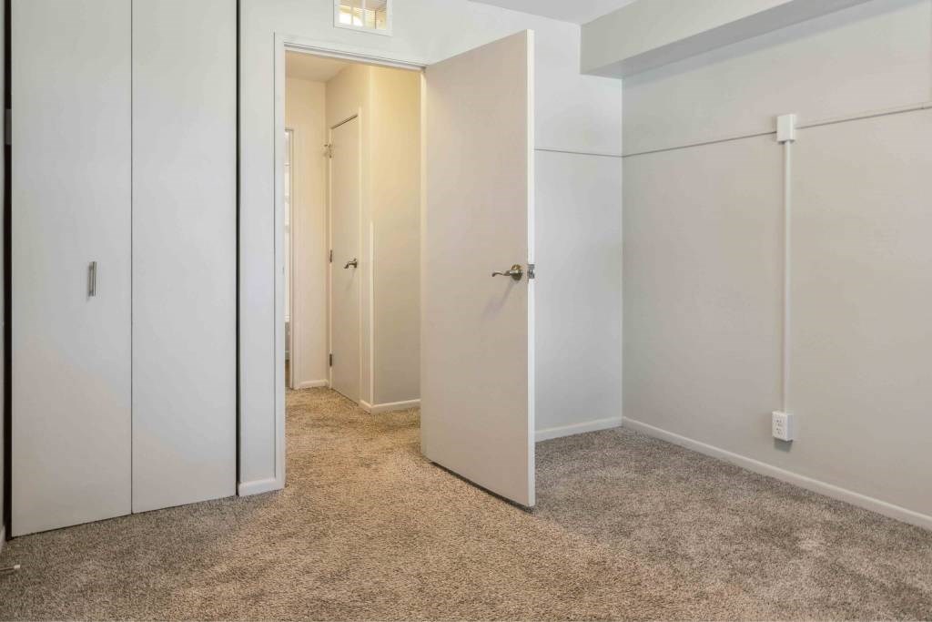 A white door is open in a room with a carpeted floor.