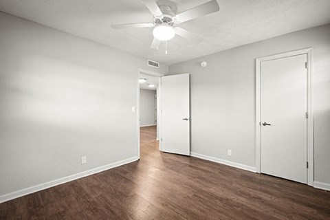 A room with a ceiling fan and three doors.