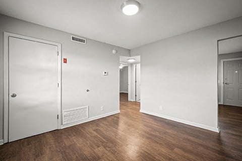 A room with a white door and a white wall with a mirror on the wall.