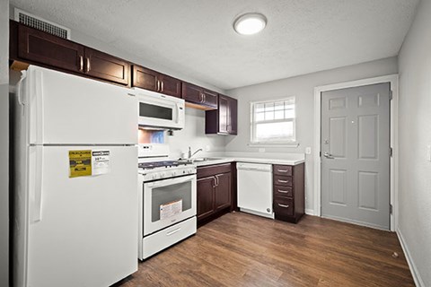 A kitchen with white appliances and brown cabinets.