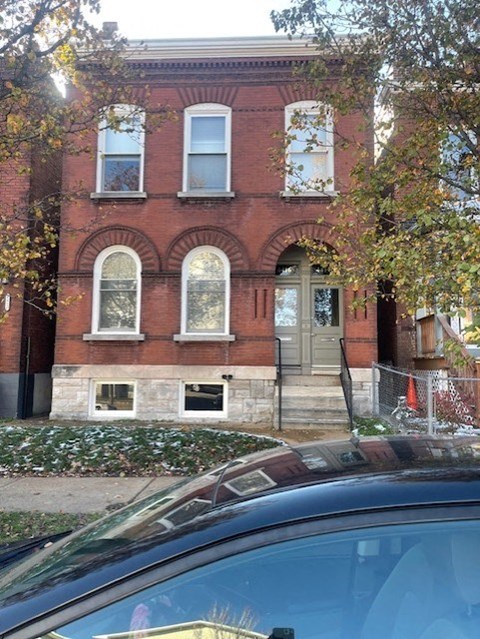 A red brick building with a black car in front.