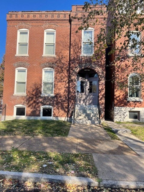 A red brick building with a white door and windows.