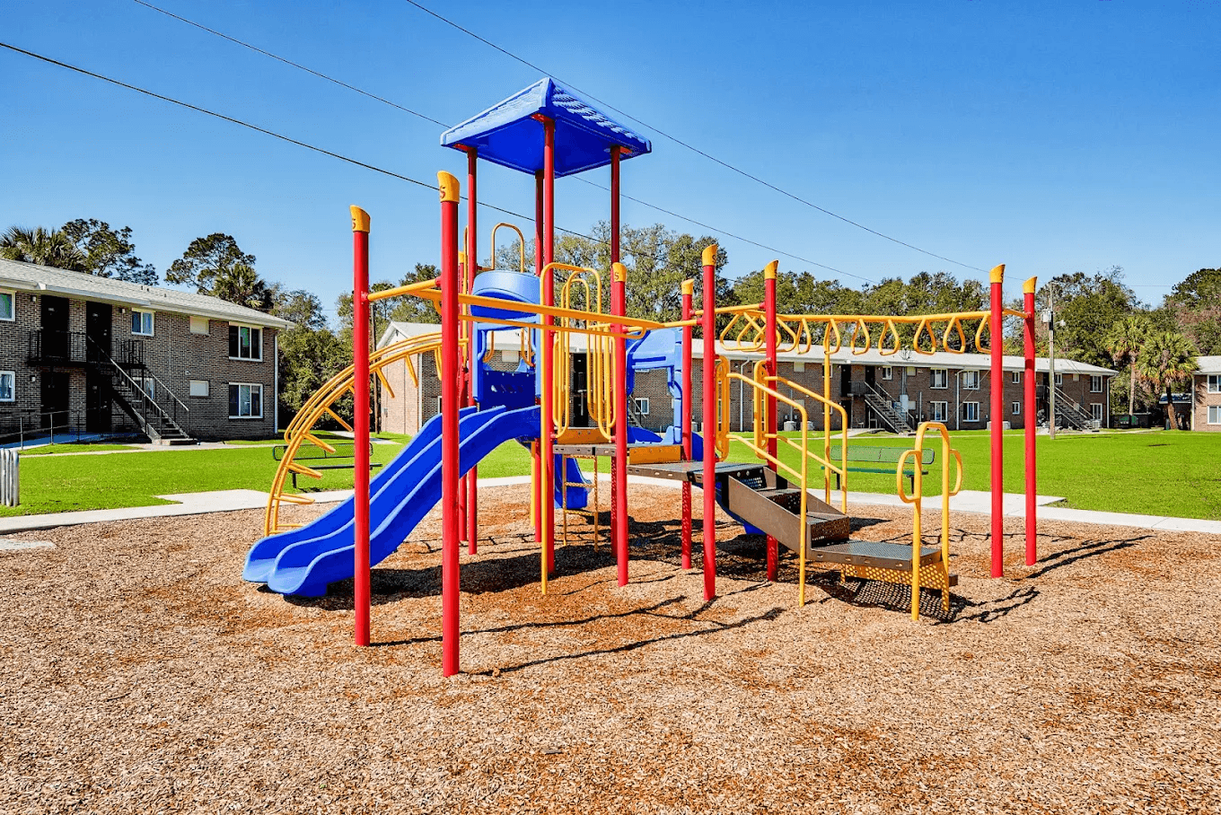 A playground with a blue slide and yellow and red structures.