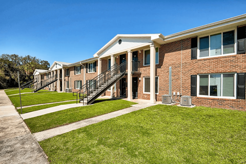 A row of houses with green lawns in front.