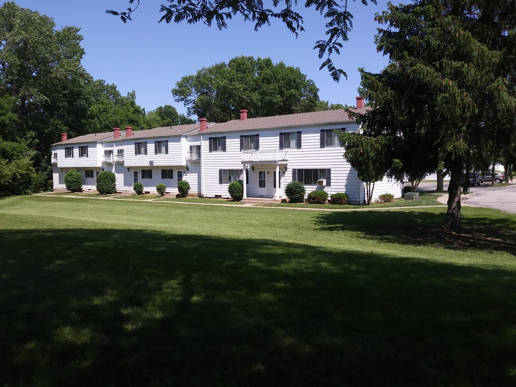 A white building with a green lawn in front.