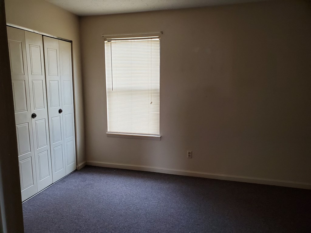 an empty room with a window and a closet