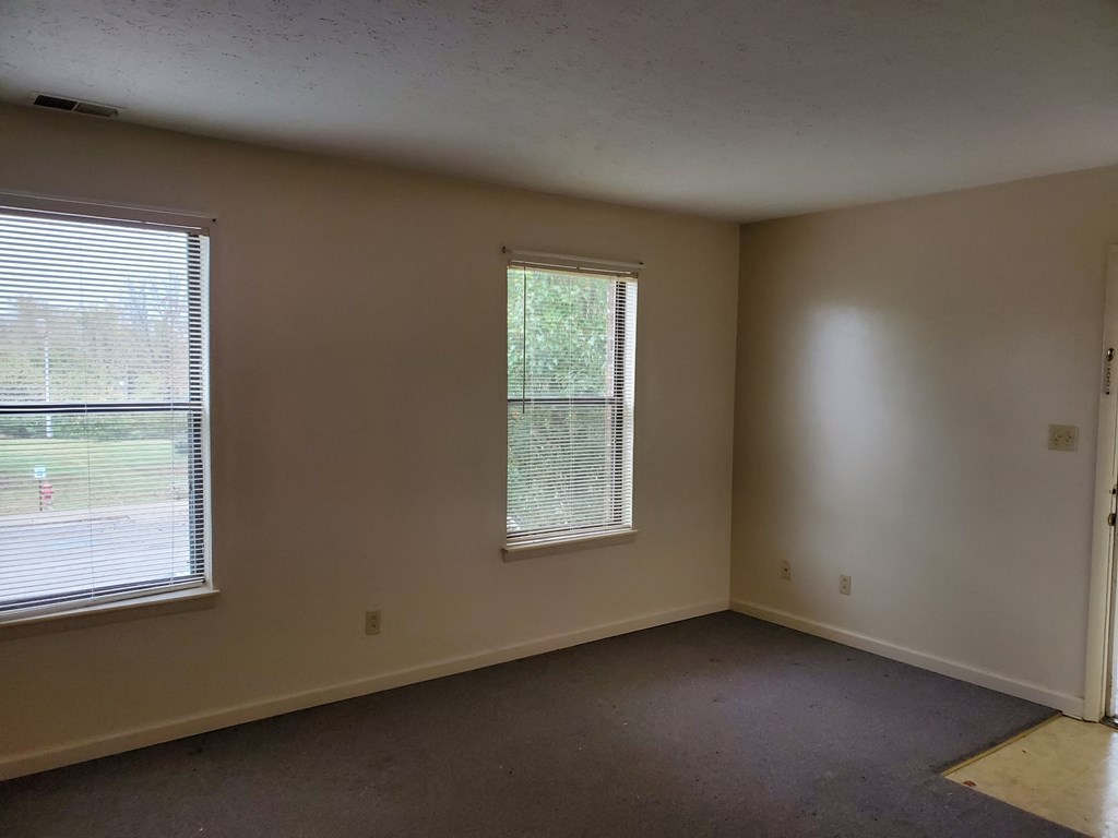 an empty room with two windows in it
