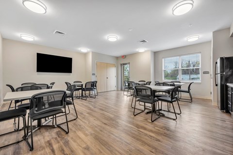 a community room with tables and chairs and a tv