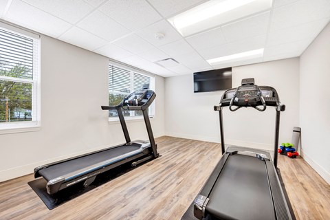 two treadmills and a television in a gym room