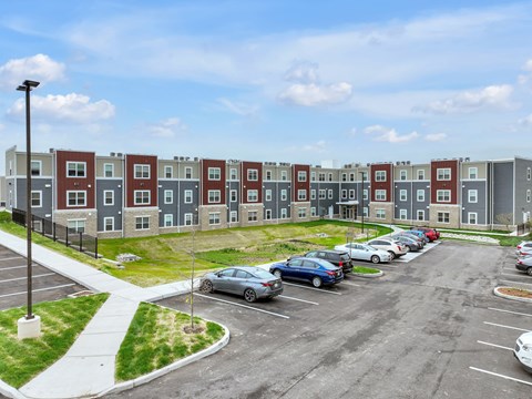 an exterior view of an apartment complex with cars in a parking lot