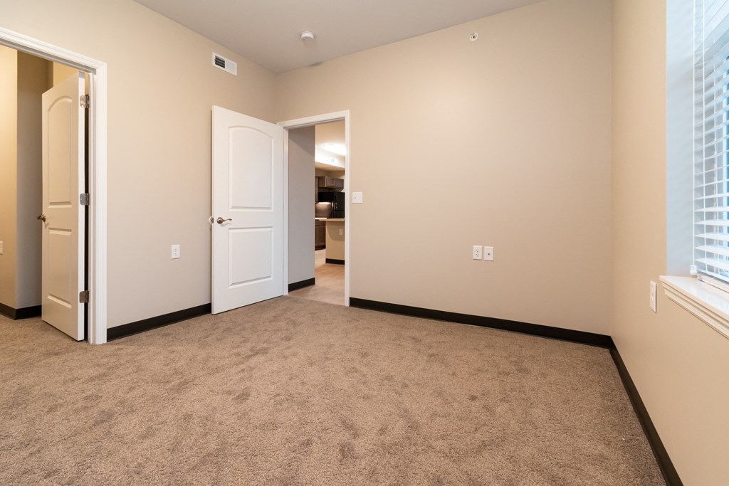 a room with a carpeted floor and an open door to a bedroom