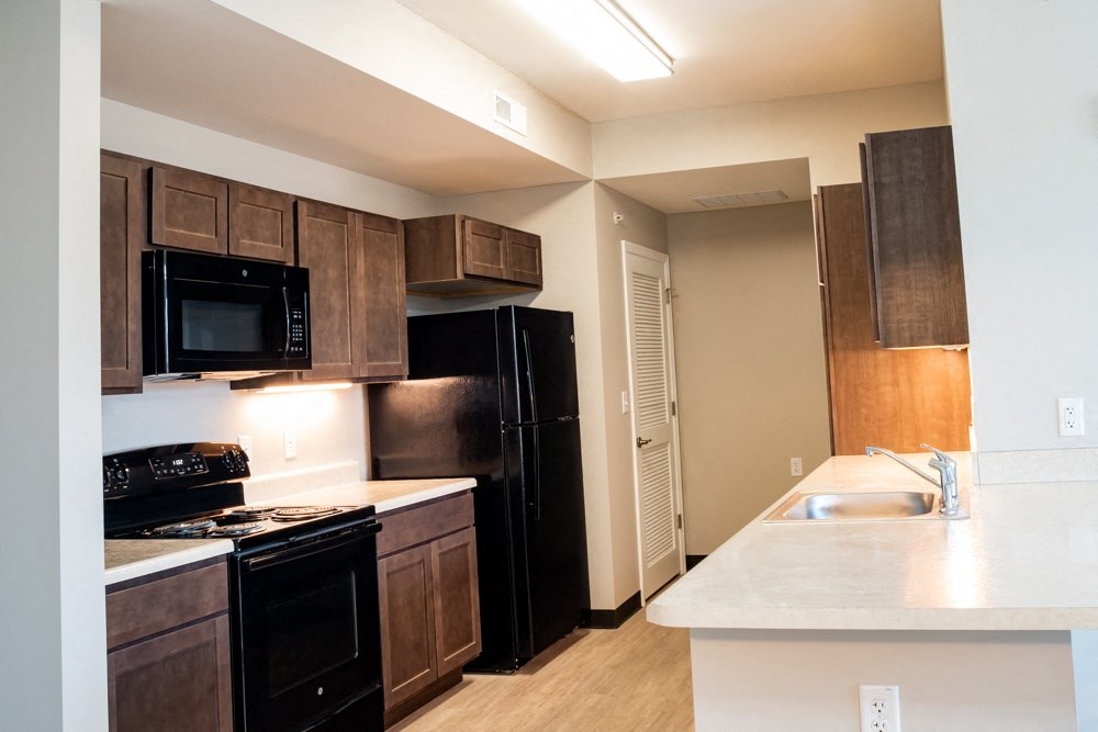 a kitchen with black appliances and wooden cabinets and a white counter top