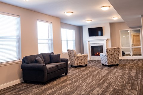 A living room with a fireplace, two chairs, and a couch.