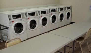 A row of white washing machines are lined up next to a white table.