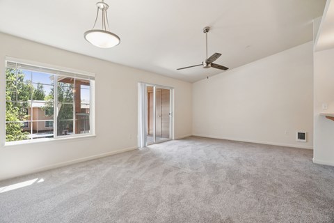 A room with a ceiling fan and a window overlooking a balcony.