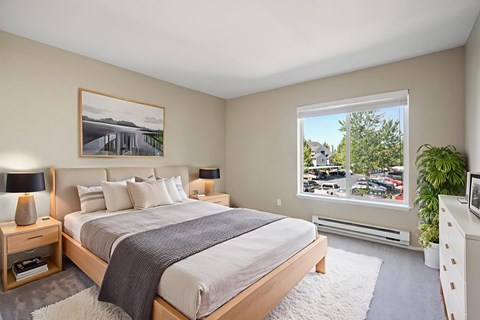 A bedroom with a large bed and a window overlooking a parking lot.