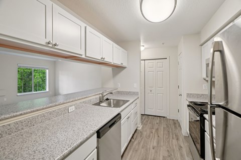 A kitchen with white cabinets and a round window.