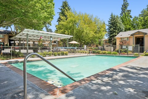 A swimming pool surrounded by a metal fence and trees.