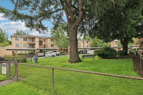 A brown fence surrounds a green lawn in front of a building.