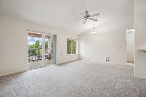 A spacious room with a ceiling fan and carpeted floor.