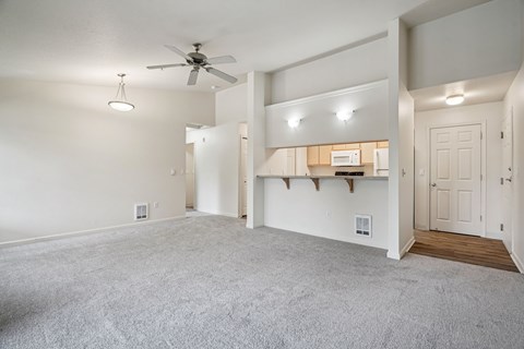 A spacious living room with a ceiling fan and a built-in shelf.