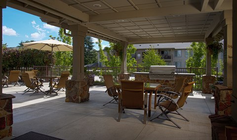 A patio with chairs and a table under a roof.