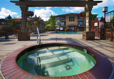 A hot tub sits in the middle of a patio area.