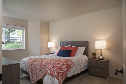 A bedroom with a bed, nightstands, and a window.