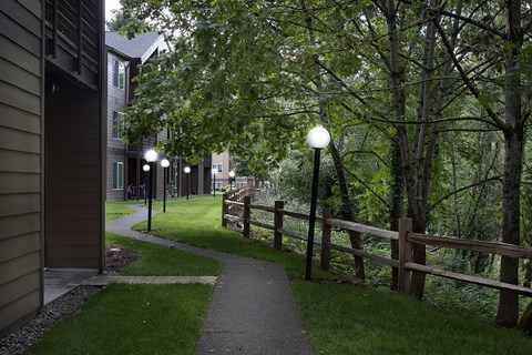 A pathway with a fence and trees on the side.